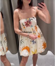 a woman taking a selfie in front of a mirror wearing a dress with flowers on it