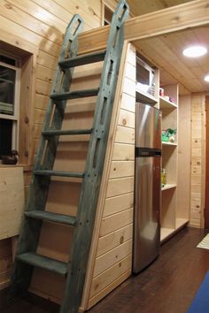 a ladder that is next to a window in a room with wood walls and flooring