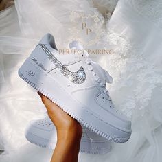 a woman's hand holding up a white nike air force shoe with diamonds on it