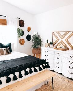 a white bedroom with black and white decor on the walls, bedding and dressers