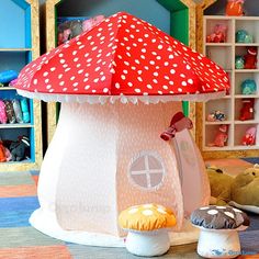 a red and white mushroom shaped house with polka dots on it's roof, surrounded by stuffed animals