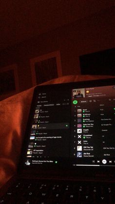 an open laptop computer sitting on top of a bed in the dark with green lights