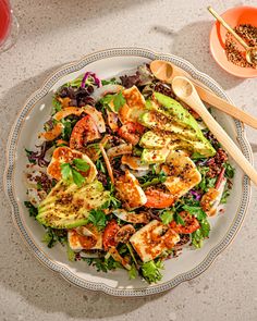 a salad with shrimp and lettuce on a white plate next to two orange bowls