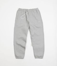 Description Nike Solo Swoosh Fleece Sweatpants Nike Solo Swoosh Fleece Sweatpants in Dark Grey Heather and White. Seen here in a traditional sportswear shade of grey, these loose fitting Nike sweatpants are crafted from a blend of 84% cotton and 16% polyester. Part of the brand’s Essentials collection, these Nike sweatpants feature a woven elastic waistband, internal drawstring adjusters and two mirrored drop-in pockets. Finished with tonal stitched seams and with a white embroidered Swoosh sewn Grey Sweatpants Men, Nike Grey Sweatpants, Grey Nike Joggers, Best Joggers, Sweatpants Nike, Pants Outfit Men, Skate Culture, Everyday Casual Outfits, Grey Sweats