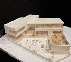 an architectural model of a house on top of a white surface with flowers in the foreground