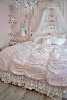 a pink bedroom with white bedding and chandelier