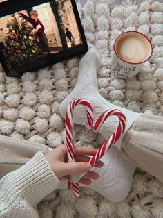 someone is holding two candy canes in front of their feet while they are on the bed