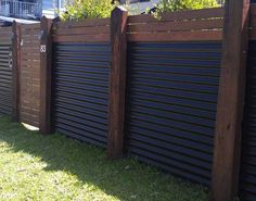 a wooden fence with metal slats on the top and bottom, in front of a house