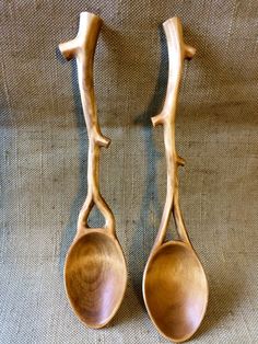 two wooden spoons sitting next to each other on top of a cloth covered surface