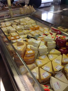 many different types of cheese on display in a store