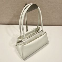 SHOP MORE LUXURY PRODUCTS HERE Description Prada Small Bag White For Women, Women’s Bags 9.8in/25cm 1BA368_2DDJ_F0009_V_OOO A study of the lines characterizes this smallÃƒÂ¯Ã‚Â¿Ã‚Â½ÃƒÂ¯Ã‚Â¿Ã‚Â½ÃƒÂ¯Ã‚Â¿Ã‚Â½ÃƒÂ¯Ã‚Â¿Ã‚Â½ handbag. It stands out for its absolutely elegant silhouette emphasized by the long, narrow handle. This three-pocket accessory is decorated with the metal lettering logo. Size: 25 x 13.5 x 13 cm /9.8 x 5.3 x 5 inches (Length x Width x Height) WhiteHandlesMetal hardwarePrinte Classic Pouch Baguette Bag With Top Carry Handle, Classic Baguette Bag With Top Carry Handle, White Double Handle Baguette Bag For Errands, White Leather Baguette Bag With Top Carry Handle, White Baguette Bag With Double Handle For Travel, White Baguette Bag With Top Carry Handle For Travel, White Double Handle Baguette Bag For Travel, Satchel Baguette Bag With Top Carry Handle For Errands, Baguette Bag With Top Carry Handle