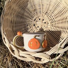 a coffee cup sitting on top of a wicker basket next to two small pumpkins