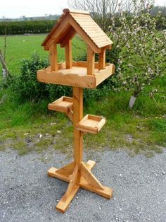 a wooden bird house sitting on top of a stand in the middle of a field