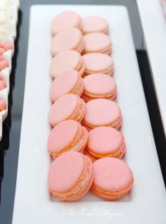 there are many pink and white macaroons on the plate next to each other