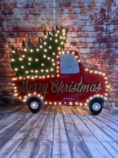 a red truck with a christmas tree on the back in front of a brick wall