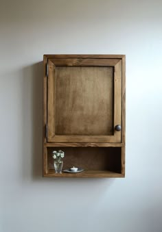 a wooden shelf with some flowers in it and a vase on the wall next to it