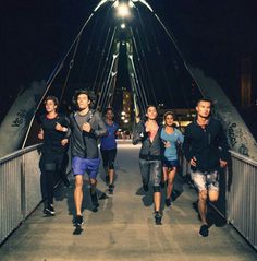 a group of people running across a bridge at night