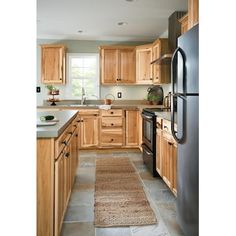 a kitchen with wooden cabinets and stainless steel appliances, along with a rug on the floor