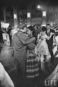 black and white photograph of people dancing at an event with their arms around each other