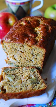 a loaf of banana bread sitting on top of a white plate next to an apple