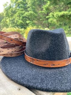 Hand-designed and tooled leather hat bands for your cowboy or rancher hat. These measure about 23.5 inches long and have an adjustable tie at the ends. Adjustable Country Hat Bands For Fall, Adjustable Hat Bands For Country Events In Fall, Rustic Leather Fedora With Adjustable Fit, Adjustable Brown Country Style Hat Bands, Rustic Adjustable Felt Hat For Festival, Artisan Adjustable Fedora For Outdoor, Adjustable Western Hat Bands For Fall, Adjustable Brown Hat Bands For Fall, Adjustable Leather Country Fedora