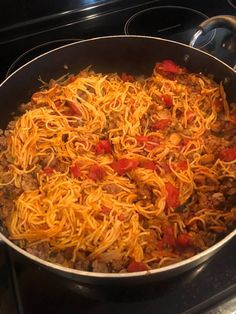 a pan filled with spaghetti and meat sitting on top of a stove