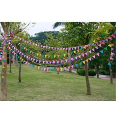 there are many colorful flags hanging from the trees in the park, and one is decorated with multicolored bunting