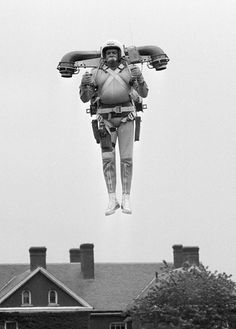 a man flying through the air on top of a kite in front of a house