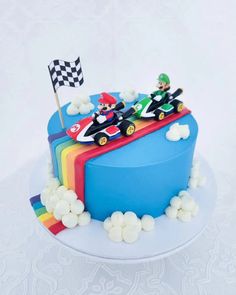 a birthday cake with mario kart and luigi on top is decorated in rainbow colors