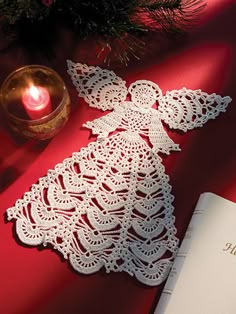 an open book sitting on top of a table next to a candle and christmas tree