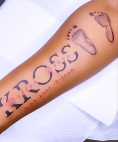 a person's arm with the word cross written on it and foot prints in black ink