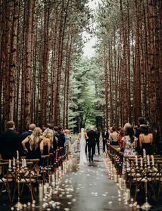 an image of a wedding in the woods with people walking down the aisle and candles on the ground