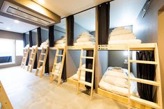 bunk beds are lined up in a room with black curtains and white sheets on them