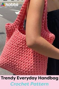 a woman carrying a pink crocheted handbag on the side of the road