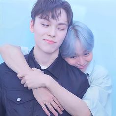 two people hugging each other in front of a blue background