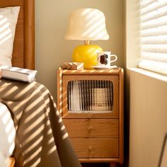 a radio sitting on top of a night stand next to a bed with pillows and blankets