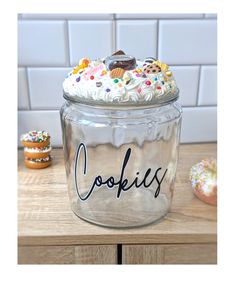 a cookie jar with frosting and sprinkles sitting on top of a wooden table