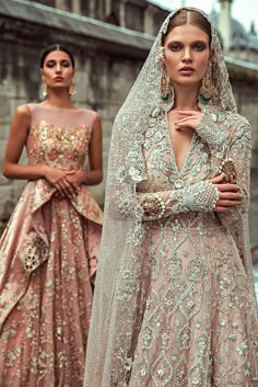 two women in wedding gowns, one wearing a veil and the other wearing a dress