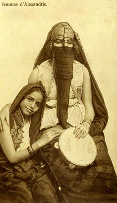 an old photo of two people sitting next to each other, one holding a musical instrument