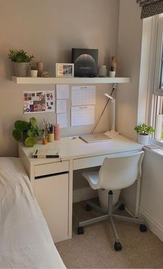 a white desk sitting under a window next to a bed