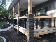 the front porch of a house with wood railings and stone pillars on both sides