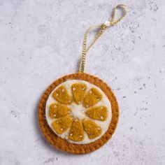 an orange ornament is hanging on a white surface with a gold chain around it