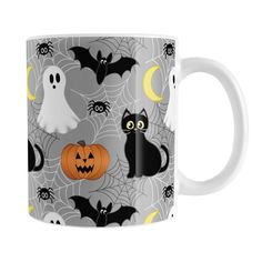 a white coffee mug with black cats, bats and pumpkins on grey background for halloween