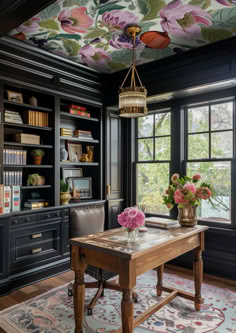 a dining room table with flowers on the ceiling and bookshelves in the background