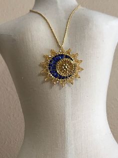 "Sun & Moon Beaded Celestial Statement Necklace.  This unique pendant is an inspirational and captivating statement piece.  It is a dramatic and eye-catching Made to Order piece which captures a delicate cool blue moon in front of a brilliant golden sun.  The pendant is stationary on a neckline of galvanized gold tiny seed beads and fastens with a gold plated lobster claw.  The pendant diameter is approximately 1 3/4\".  The shades of blue may vary.  Choose your desired length at checkout.  The pendant is dipped in floor wax to prevent the sun rays from flopping.  All materials used are Nickel/Lead Free.  Designed by Sara Landry, Dragonfly Lane and brought to life by Krina Kreations." Sara Landry, Floor Wax, Black Necklace Statement, Golden Sun, Beaded Statement Necklace, Necklace Box, White Necklace, Unique Pendant, Stunning Necklace