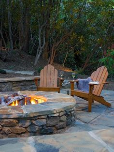 an outdoor fire pit with two chairs around it