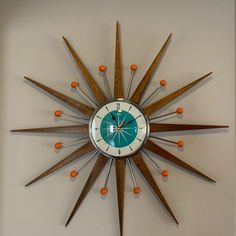 a clock that is on the wall with orange balls around it's sides and an arrow