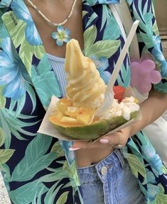 a woman is holding an ice cream sundae in her hand and wearing a flowered shirt