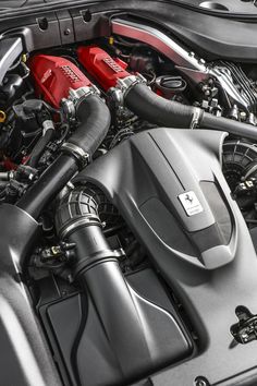 the engine compartment of a sports car with red and black accessories on it's hood