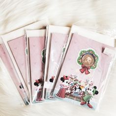 four notebooks with mickey mouse stickers on them sitting on a white fur surface